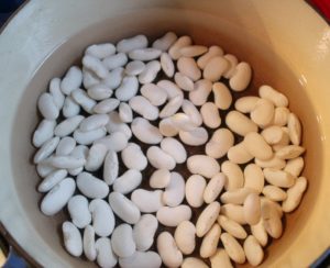 white beans soaking in pot of water